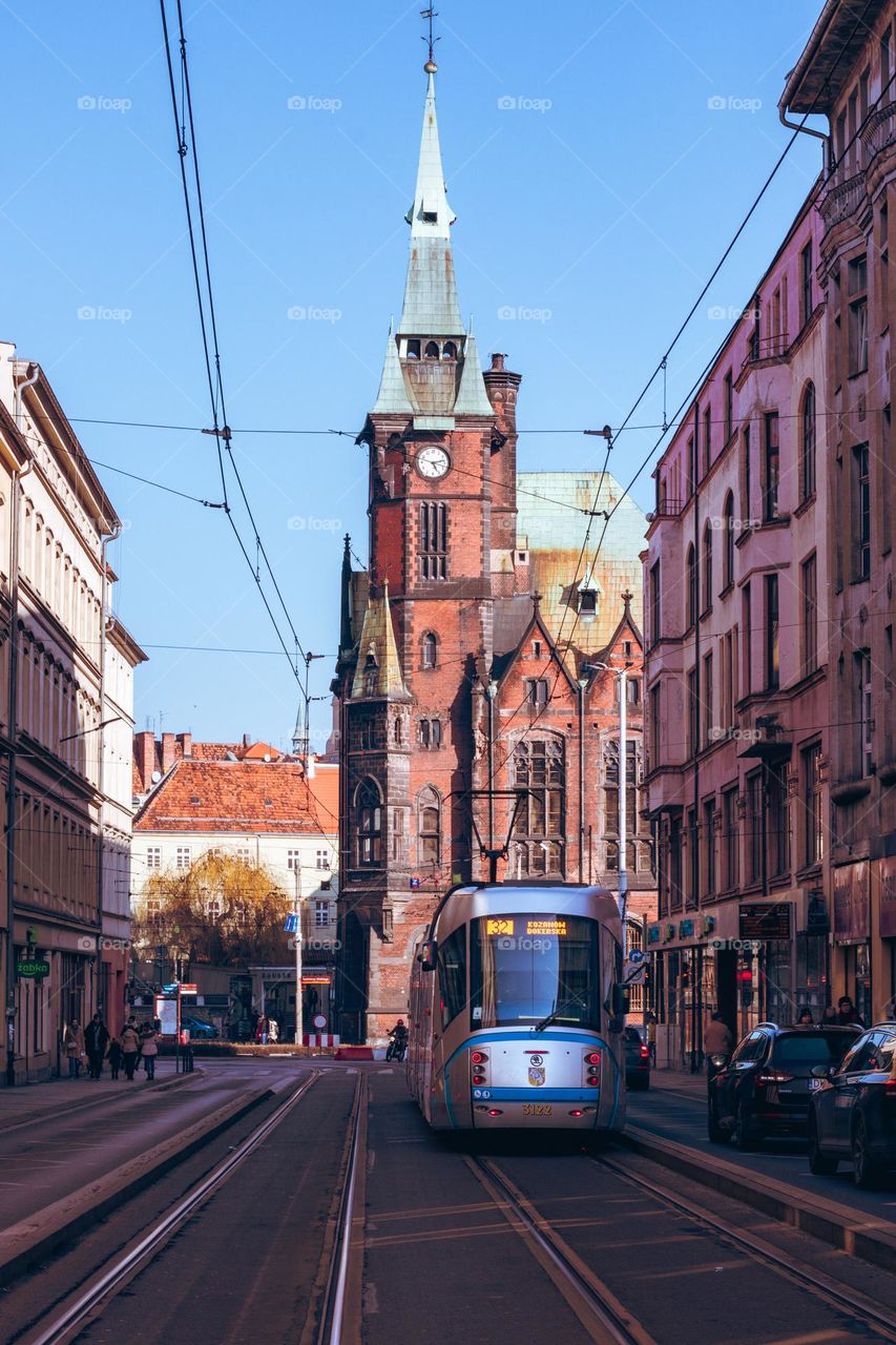 a tram rushing through the city streets in the background a historic church in Wrocław