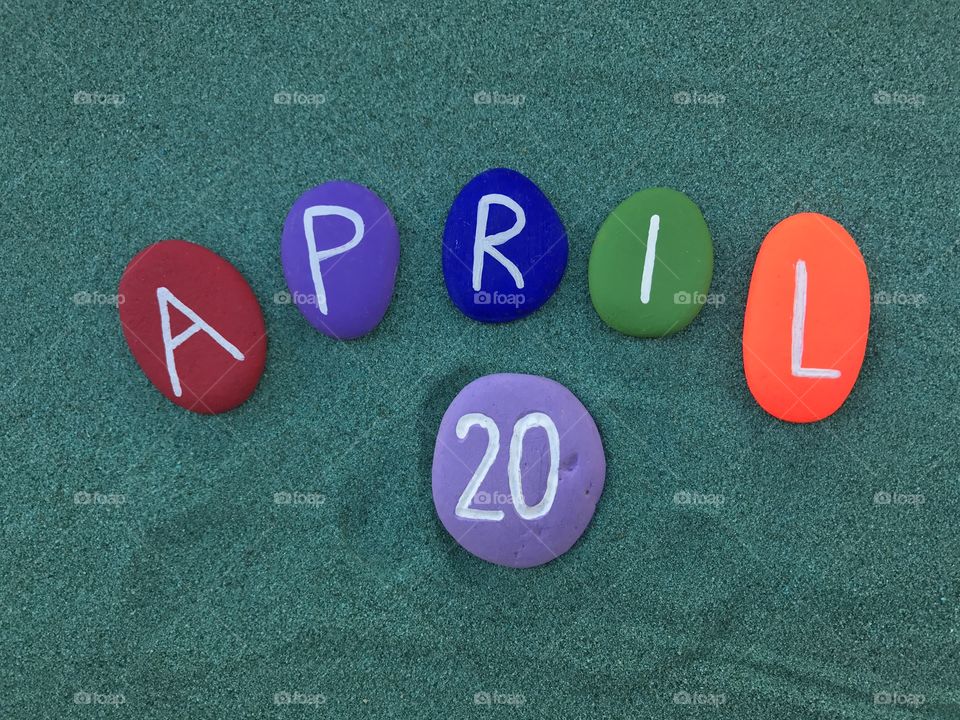 21 April, calendar date with colored stones over green sand 