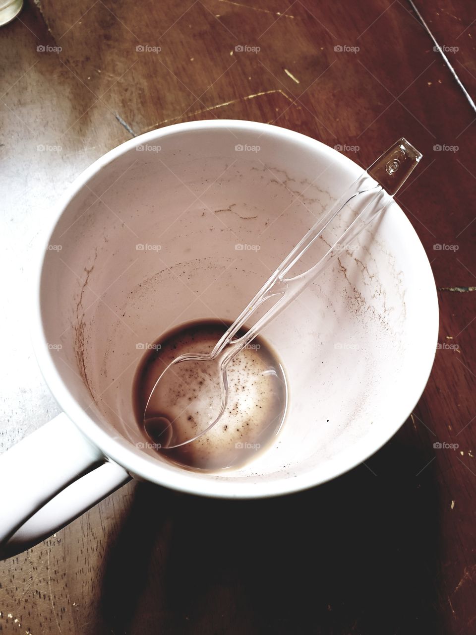 Empty coffee cup with a spoon on a wooden breakfast table, looks like breakfast is over and it's time to start our morning.