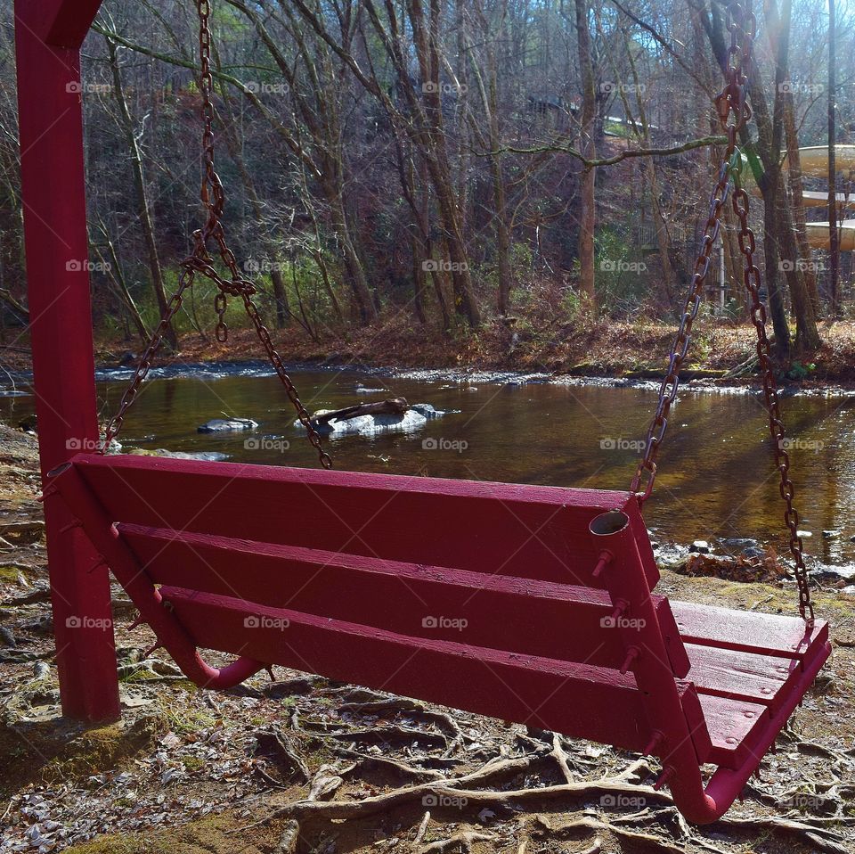 Red swing by stream