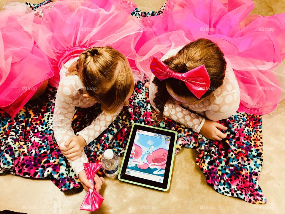 Two darling girls in pink dance costumes watching their iPad before going out to dance! 