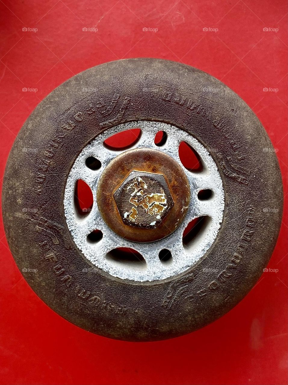 Close up of an old cracked rollerblade wheel on a bright red background