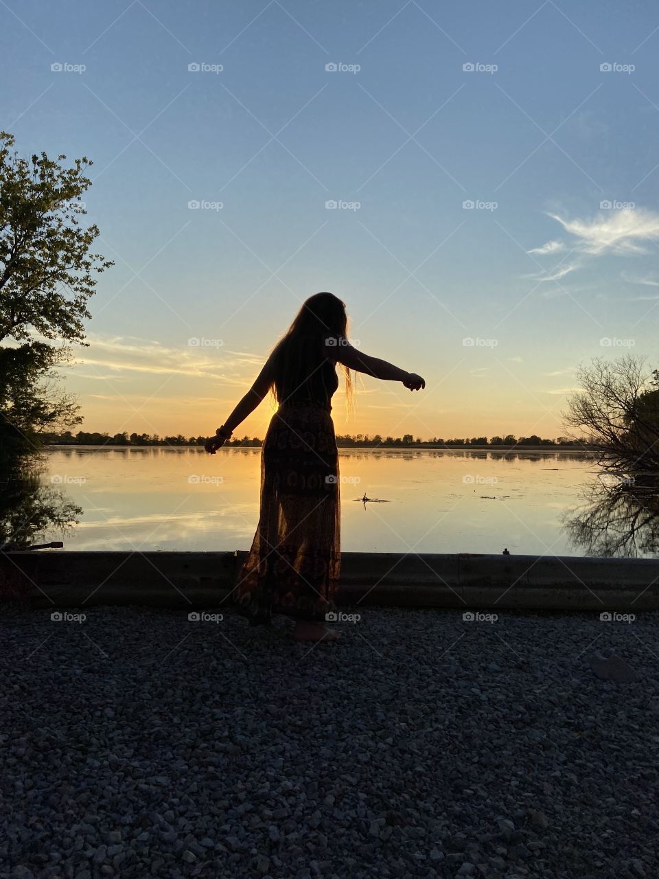 Breathtaking Silhouette of a beautiful dancing girl during golden hour sunset on the water  