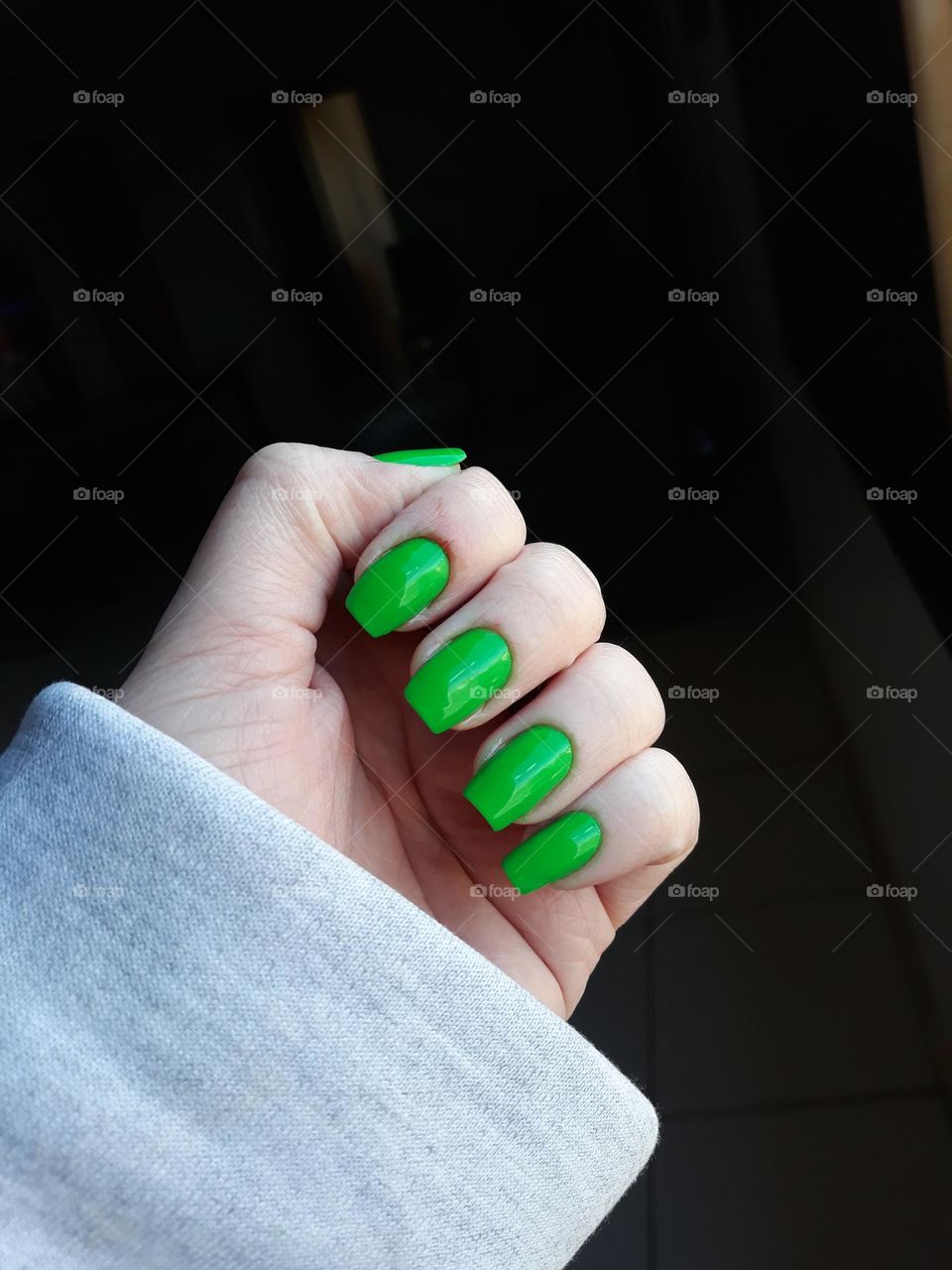 Unhas compridas pintadas com esmalte verde.