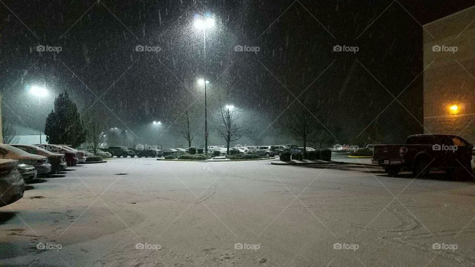 snow falling in the parking lot of a mall