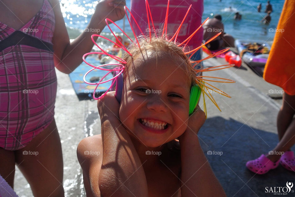 A happy child smiling because if wearing headphonenes made of a