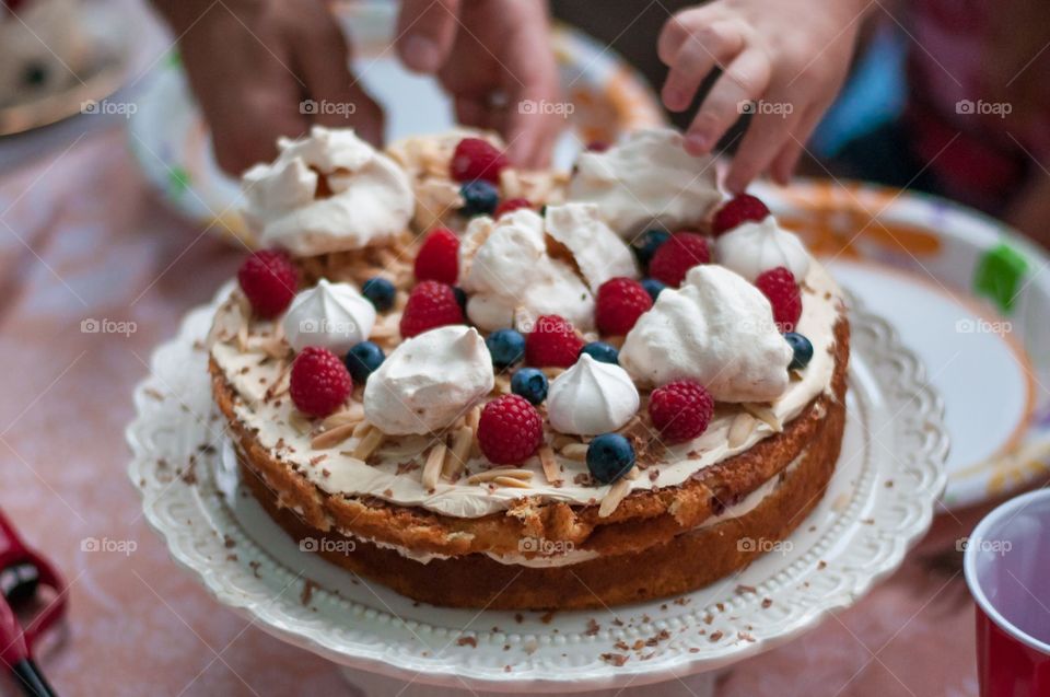 Person picking berry from cake