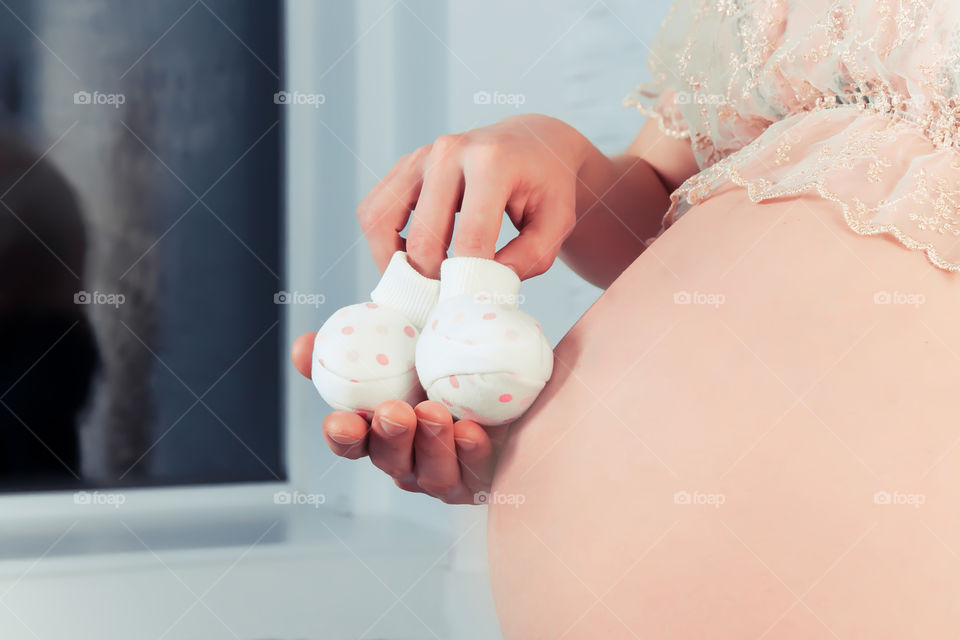 Belly of pregnant woman with a baby socks