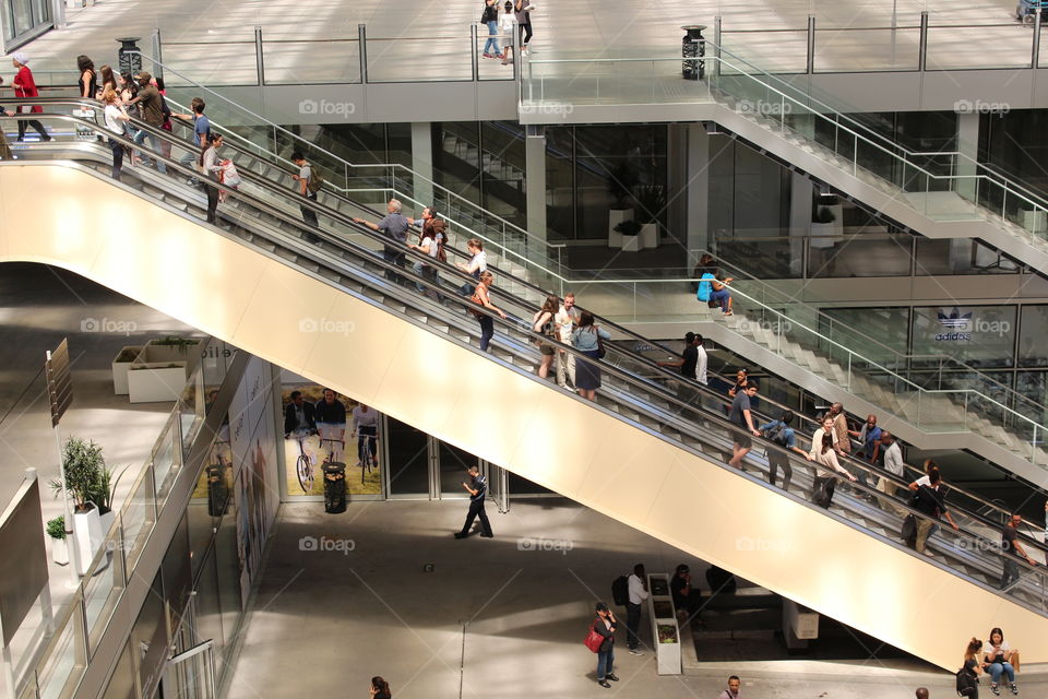 people using the escalators in an open air shopping center in Paris.