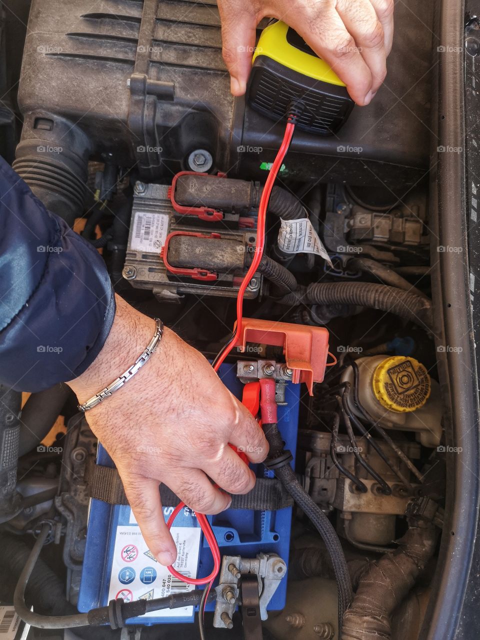 man recharges the car battery with an electric charger