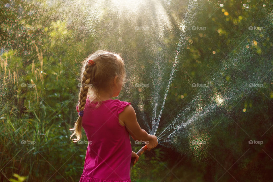 Little girl watering the plants in the garden