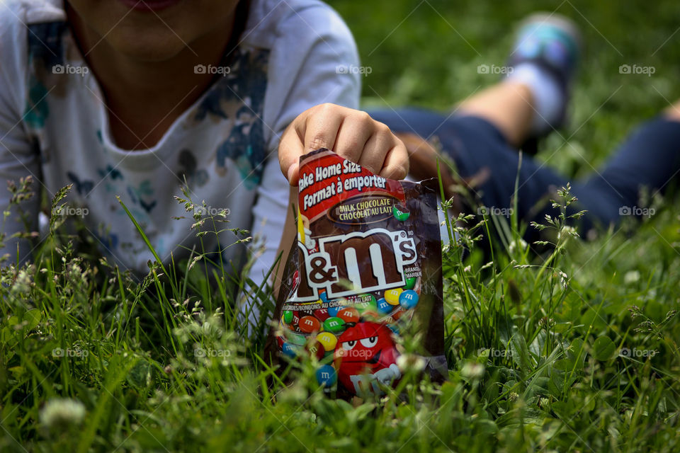 Little child in the grass with a pack of M&Ms chocolates