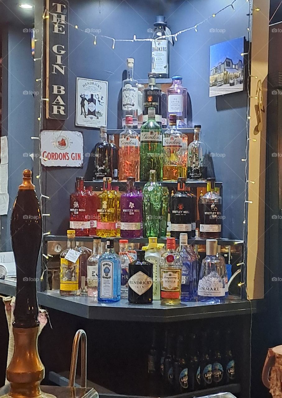 shiny coured gin bottles on shelves in pub display alcohol sell