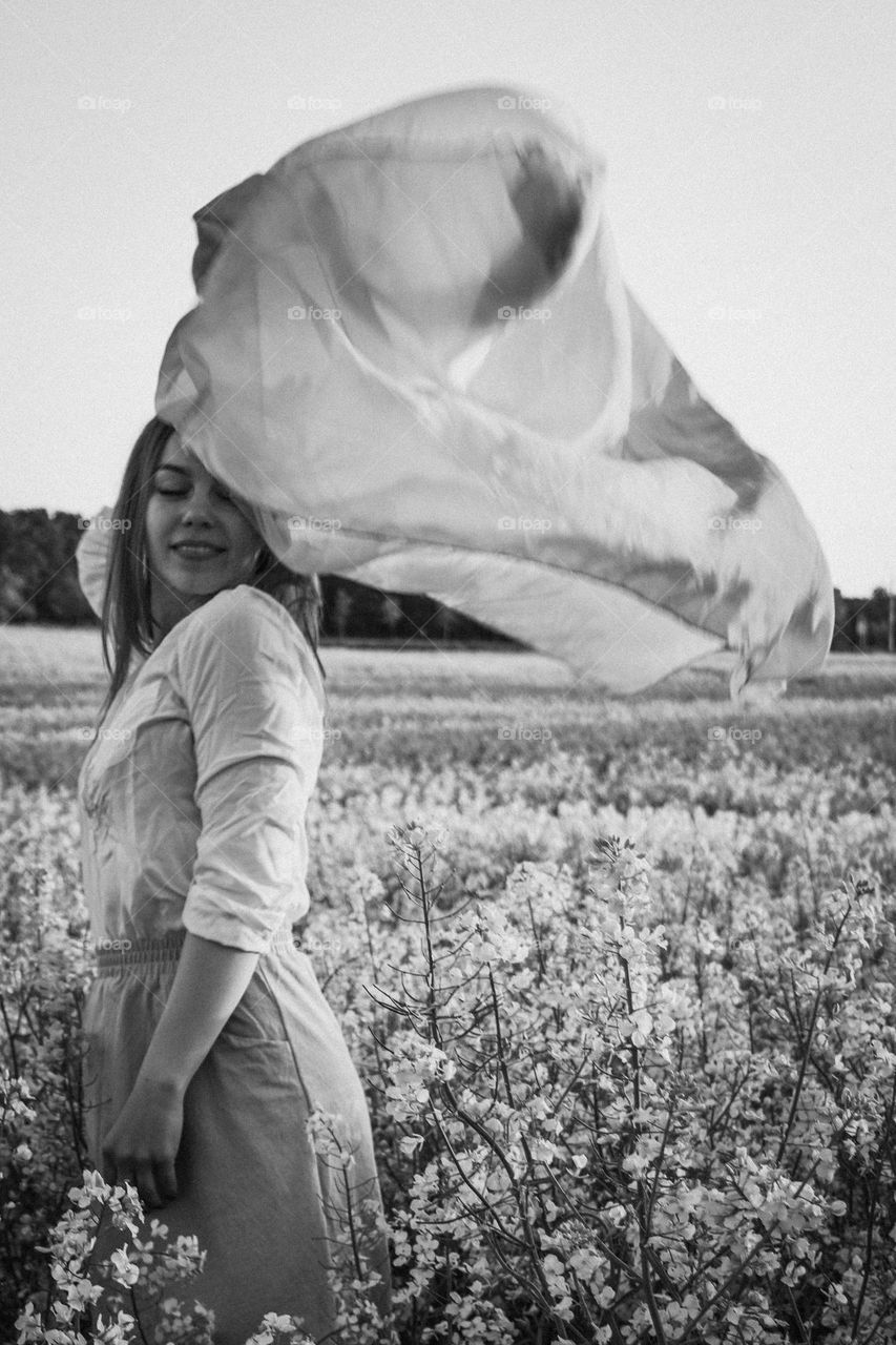 A girl with a flowy scarf in the field of flowers.