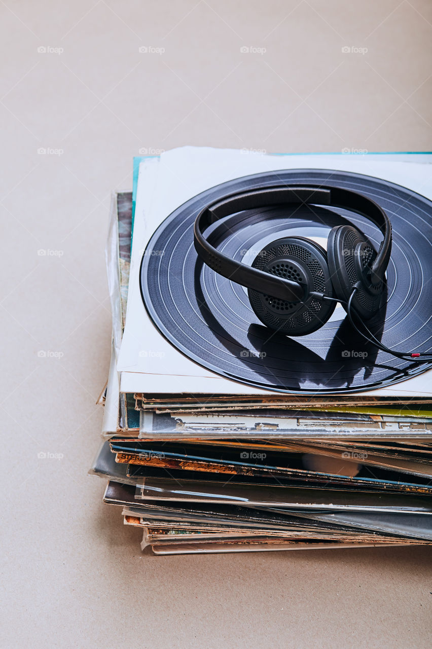 Stack of many black vinyl records and headphones on the top of stack. Candid people, real moments, authentic situations