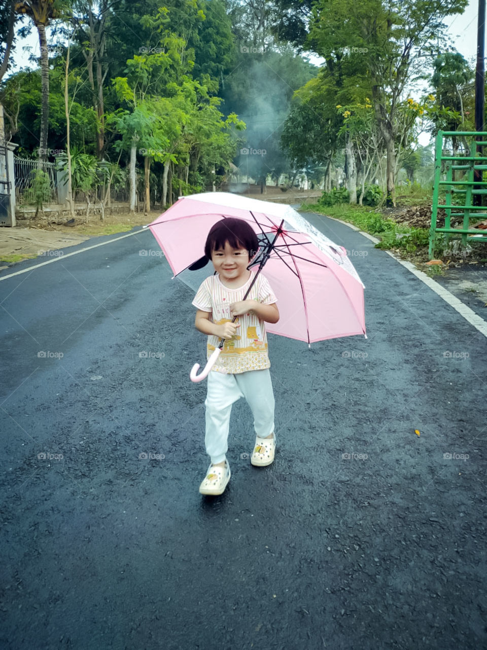 little boy walking in the rain with fun and smile