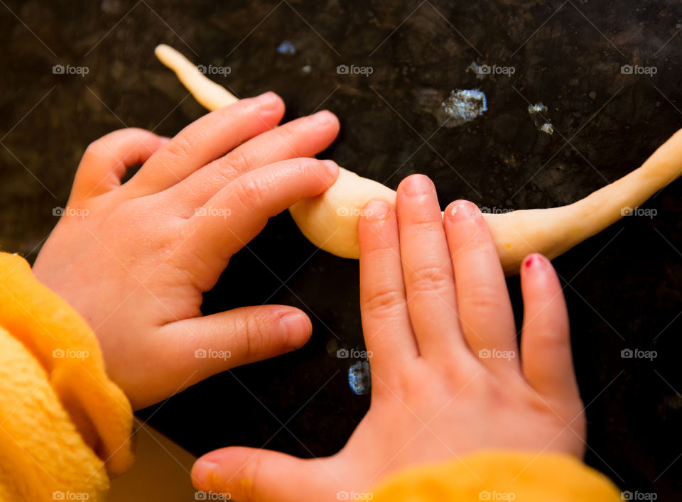 High angle view of child's hand kneading dough