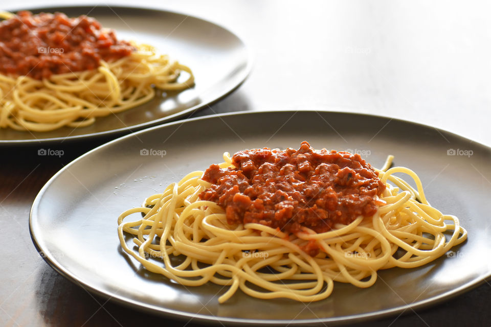 Spaghetti Bolognese with minced beef, onion, chopped tomato, garlic, olive oil, stock cube, tomato puree and Italian herb. Traditional Italian food in black plate with copy space. Selective focus.