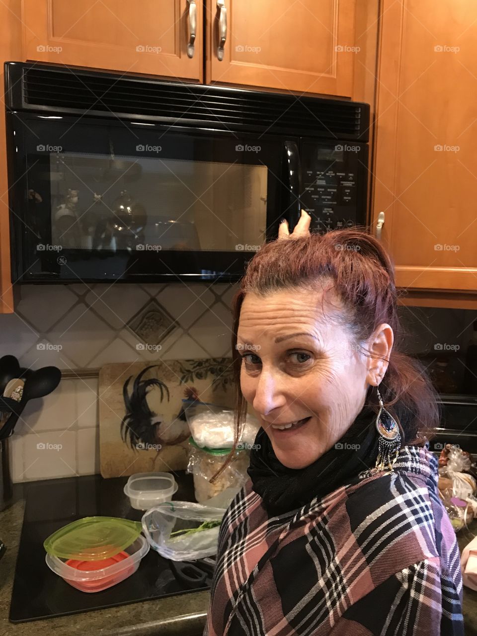 Woman in kitchen holding microwave handle