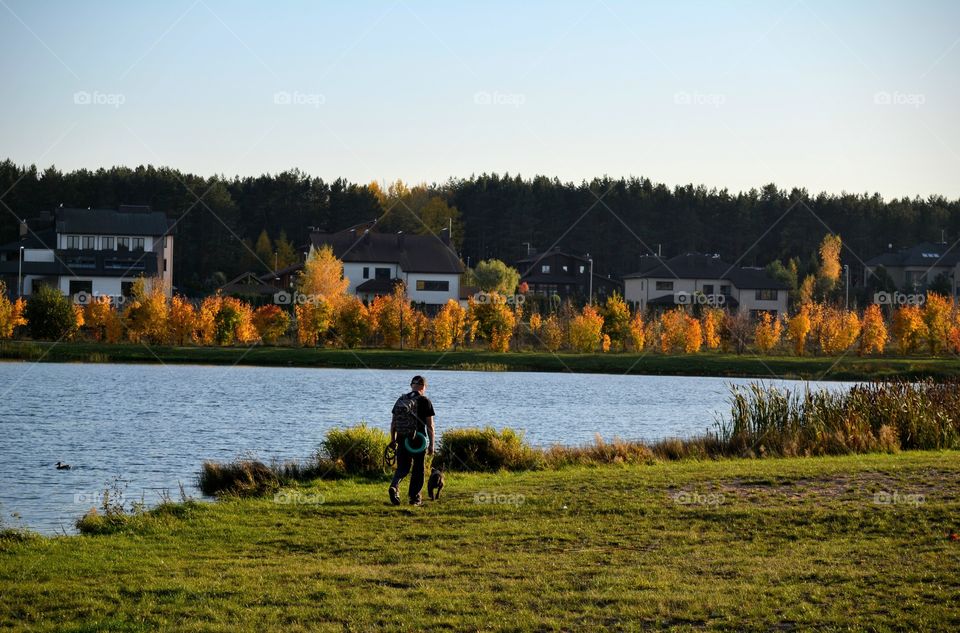 men walking with dog autumn beautiful landscape lake shore social distance