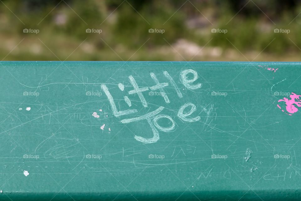 "Little Joe" graffiti scratched into paint on bridge railing 