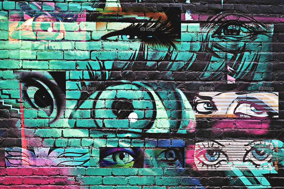 abstract graffiti street art of eyes on a brick wall on the side of a building.