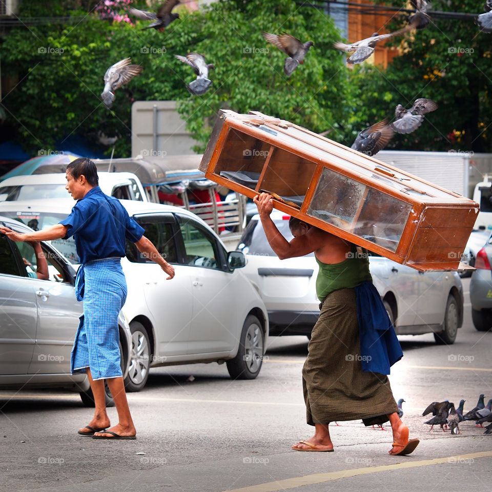 A man carrying a cupboard through the traffic