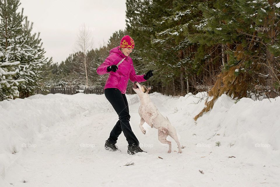 Portrait of a woman playing with her pet in snow