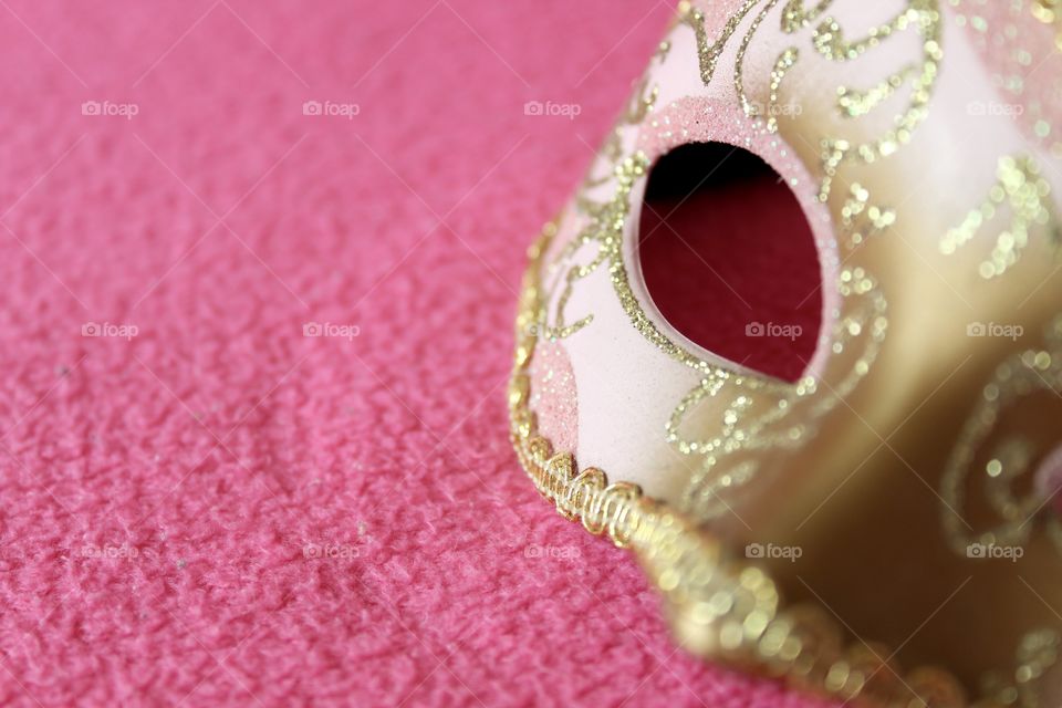 Close up of a golden mask on pink background