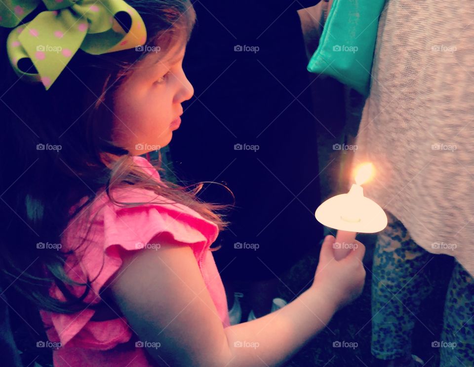 A young girl holding a candle at a candlelight vigil