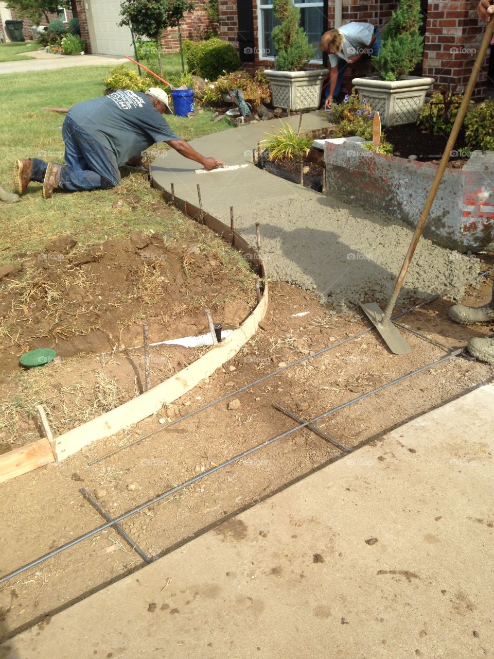 Workers pouring cement and using trowel.