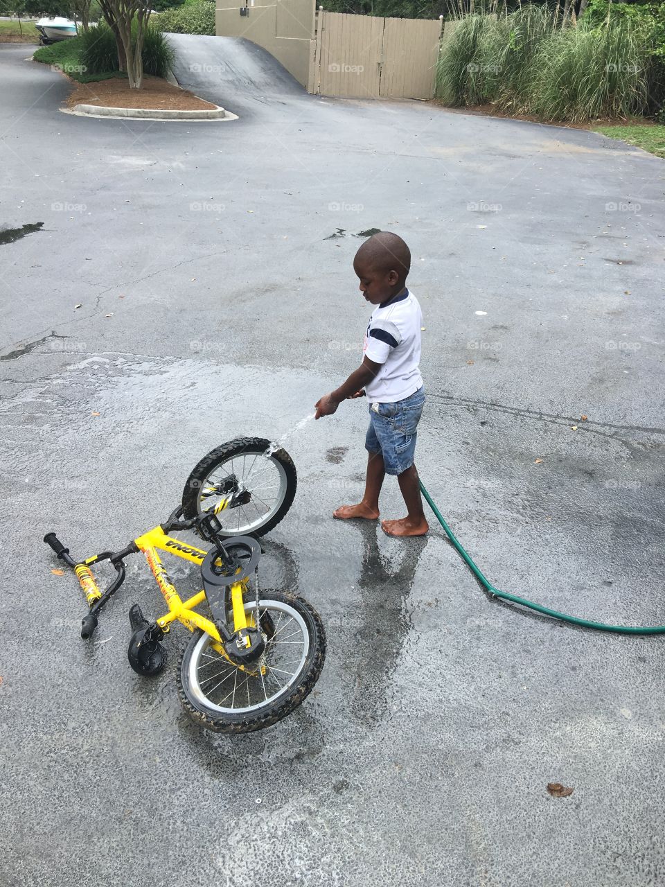 African boy washing bicycle by water