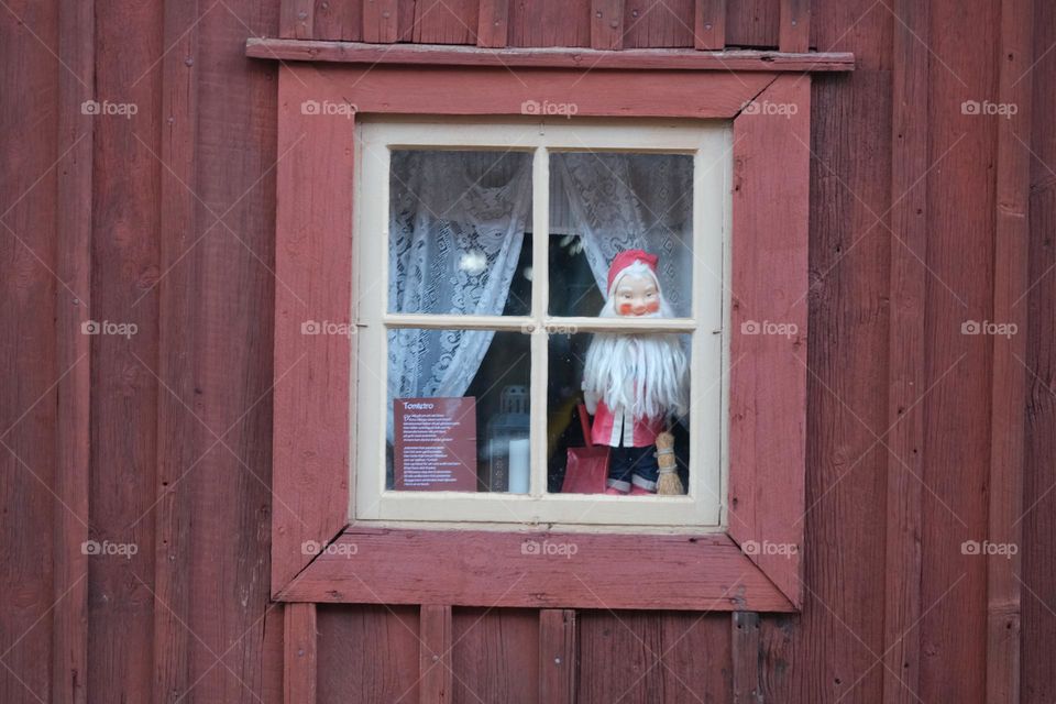 Santa Claus is watching from a window of a traditional swedish house