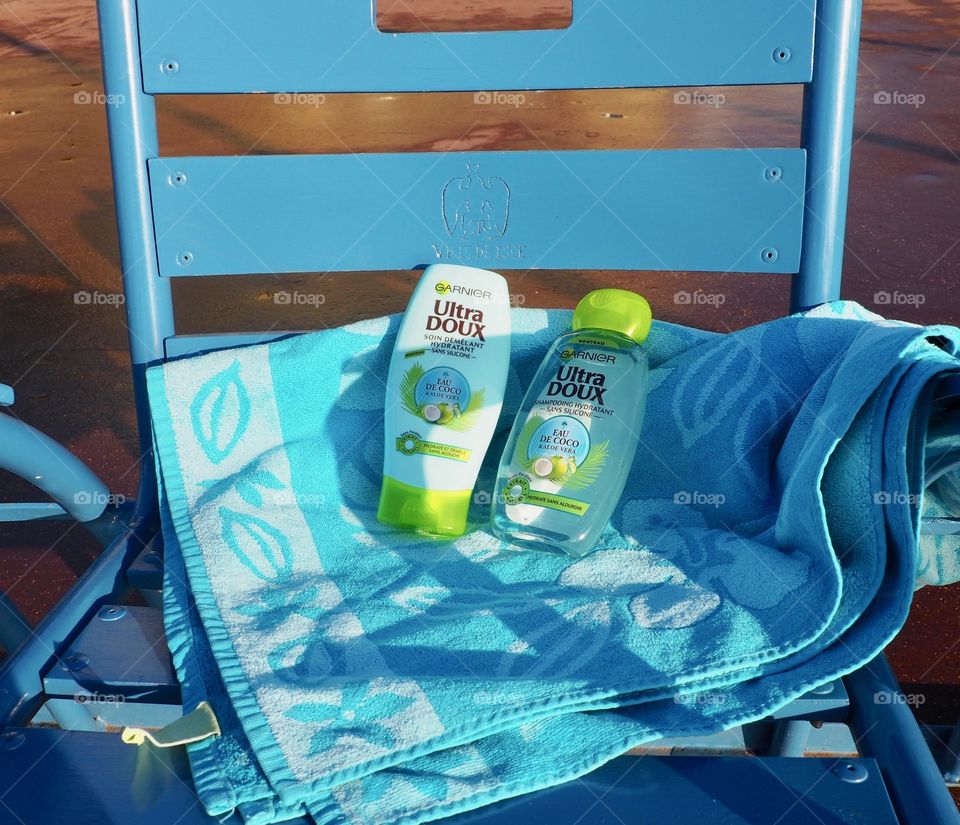 Garnier eau de coco on a blue beach towel in a blue chair in Nice, France.