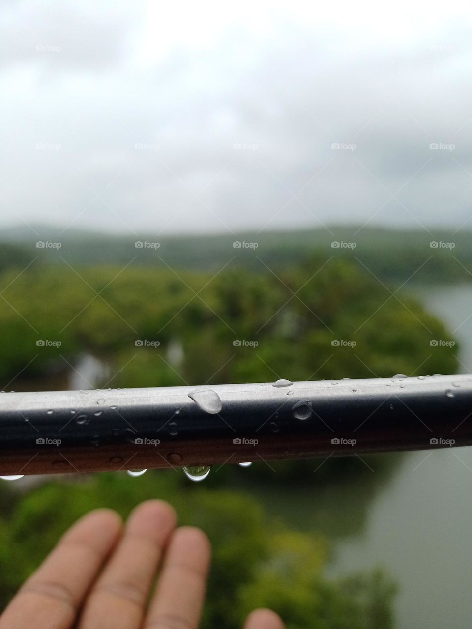 a human hand with water drops enjoying the rain drops with train journey in rainy season clousup photo