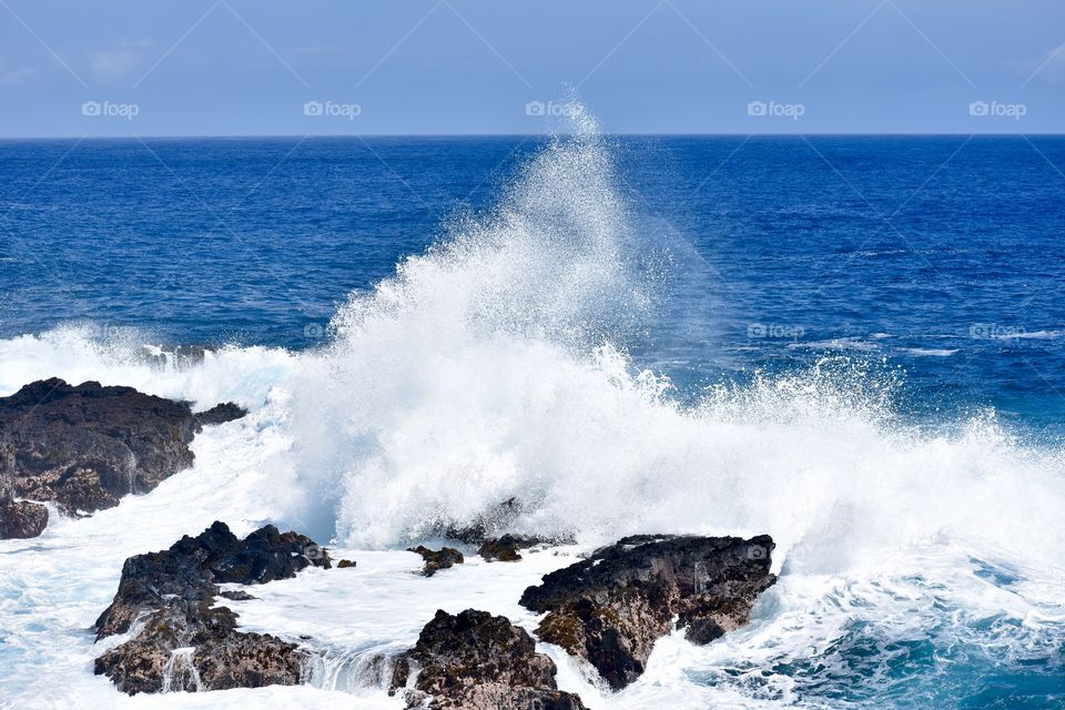 A big splash on a lava rock outcropping on the east side of the Big Island of Hawaii.