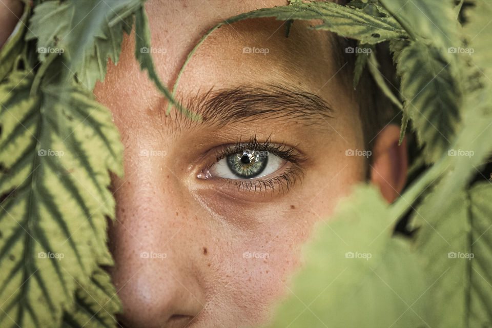 Close-up portrait of boy looking through plants .
