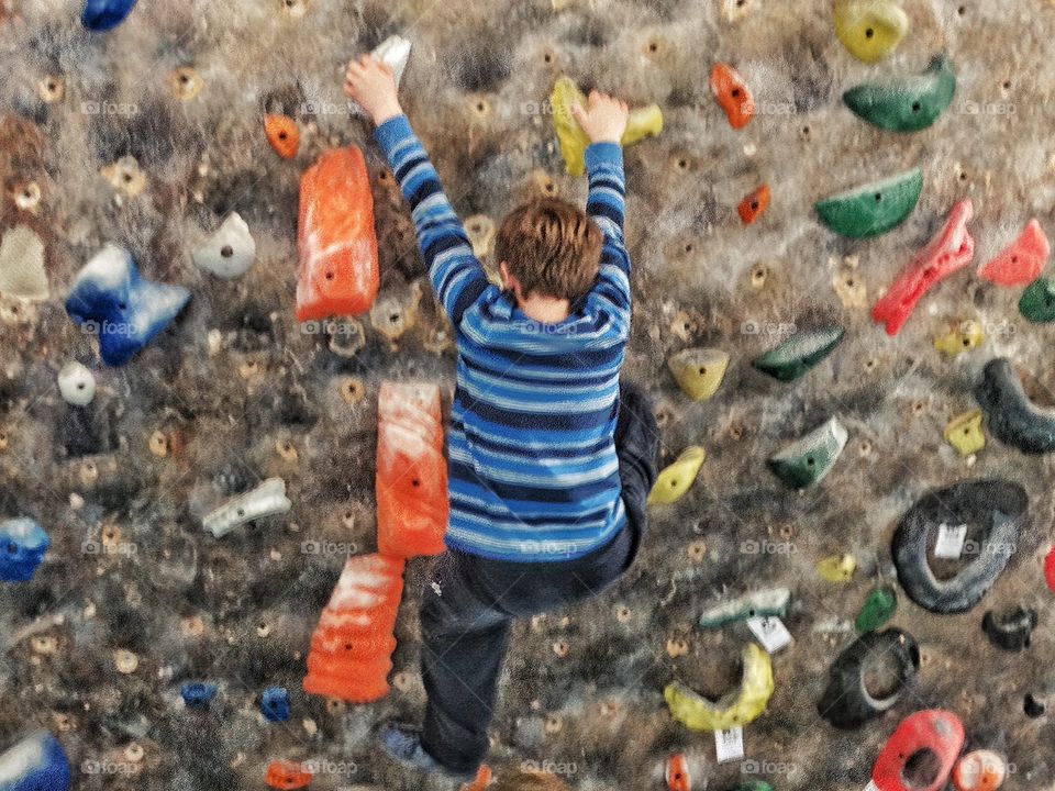 Boy Climbing A Rock Wall
