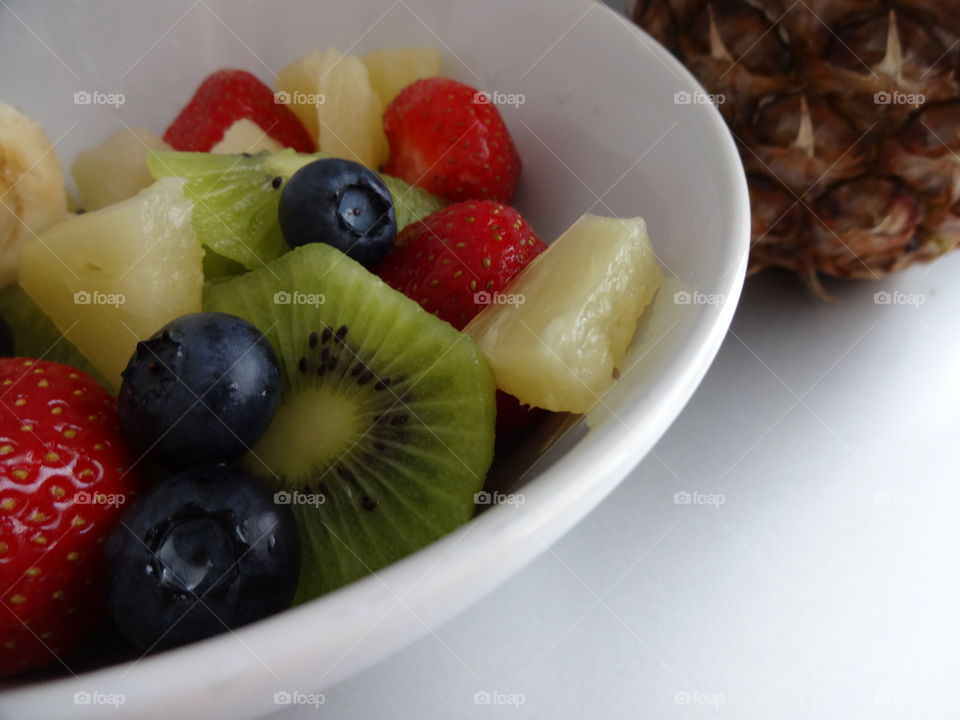 Healthy fruits breakfast full of vitamins with strawberry, kiwi, banana, pineapple and berries