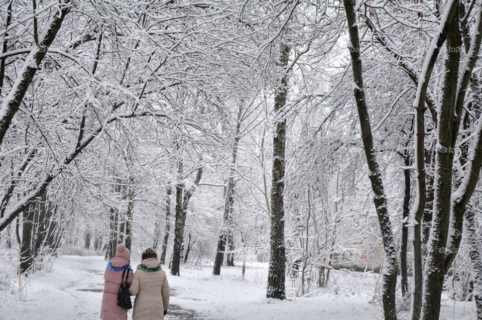 mother and daughter walking in winter snowy park, beautiful covered trees texture, Christmas time, nature lover