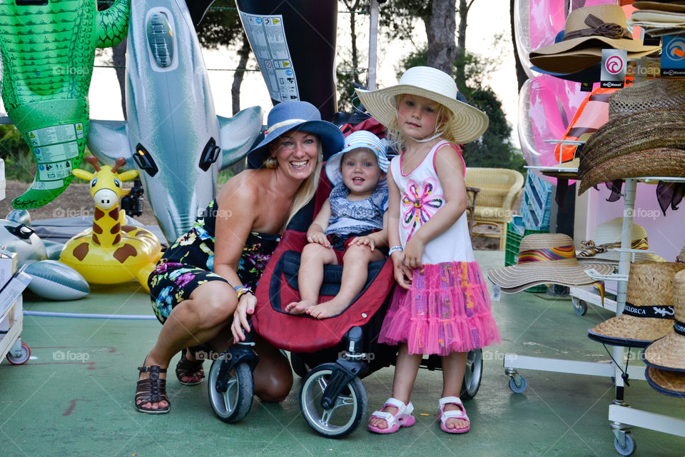 Mom with her doughters trying out hats on a market in Majorca Spain.