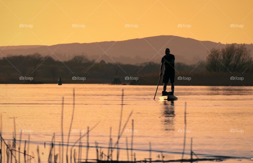 Stand up peddle boarder at sunset in Corrib river, Galway, Ireland