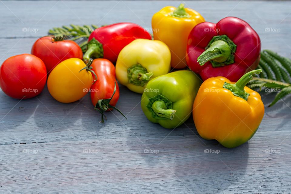 Vegetables red and yellow bell peppers and tomatoes on a blue wooden background. Fintes food