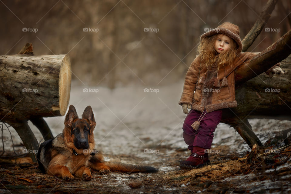 Little girl with German shepherd dog in a spring park 