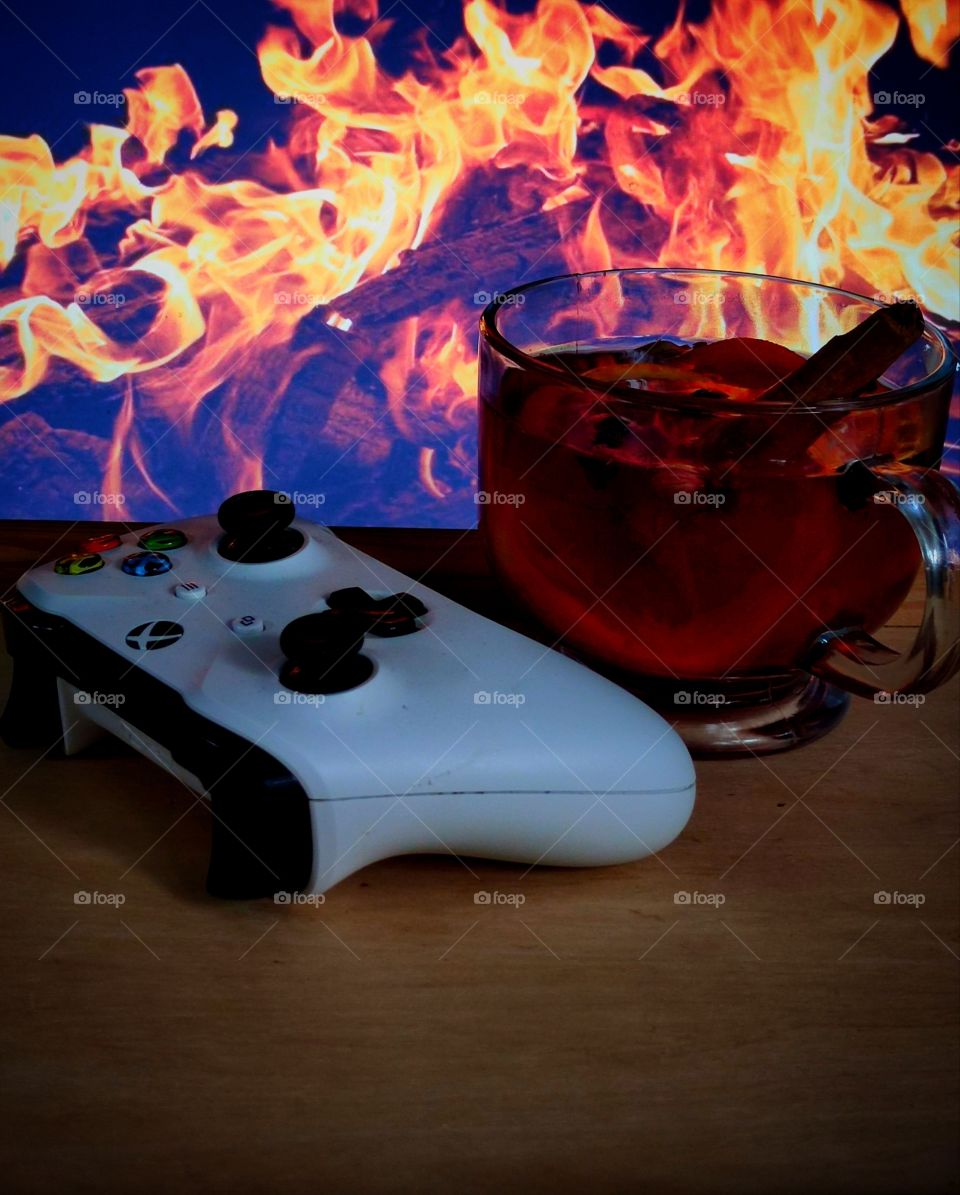 Evening.  There is a wooden table in front of the fireplace with a gamepad and a mug of warm mulled wine