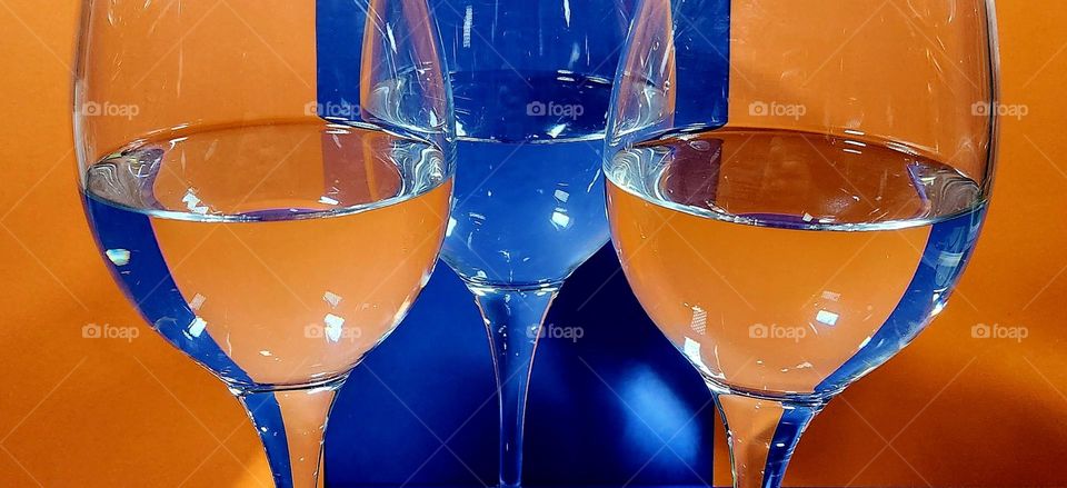 Orange and blue complementary colours composition made with orange and blue papers reflecting in half filled water glasses