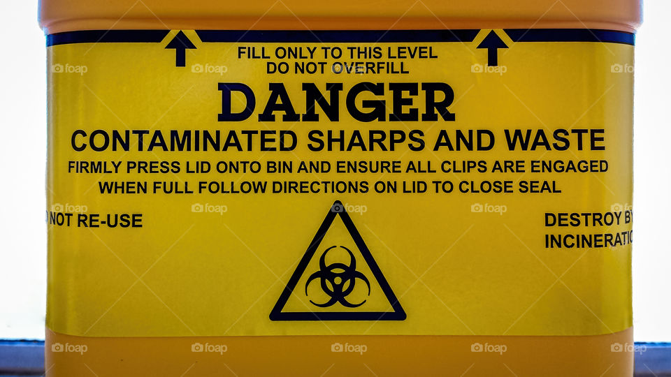 Warning and safety information label on a sharps bin or container.