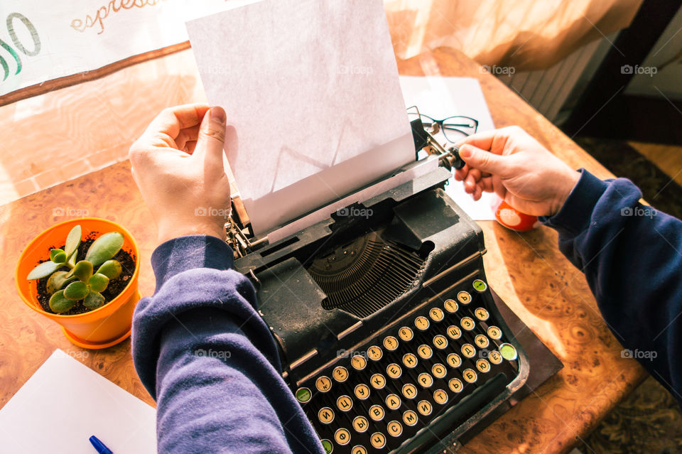 A young writer is writing his new book on his old typewriter.