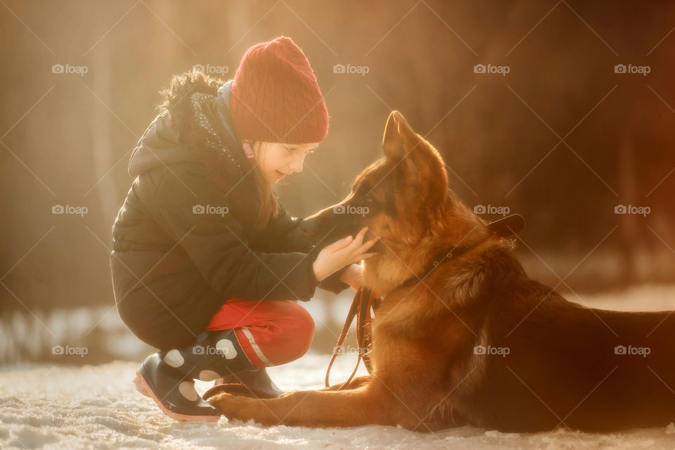 Girl portrait with German shepherd puppy in a spring forest at sunset 