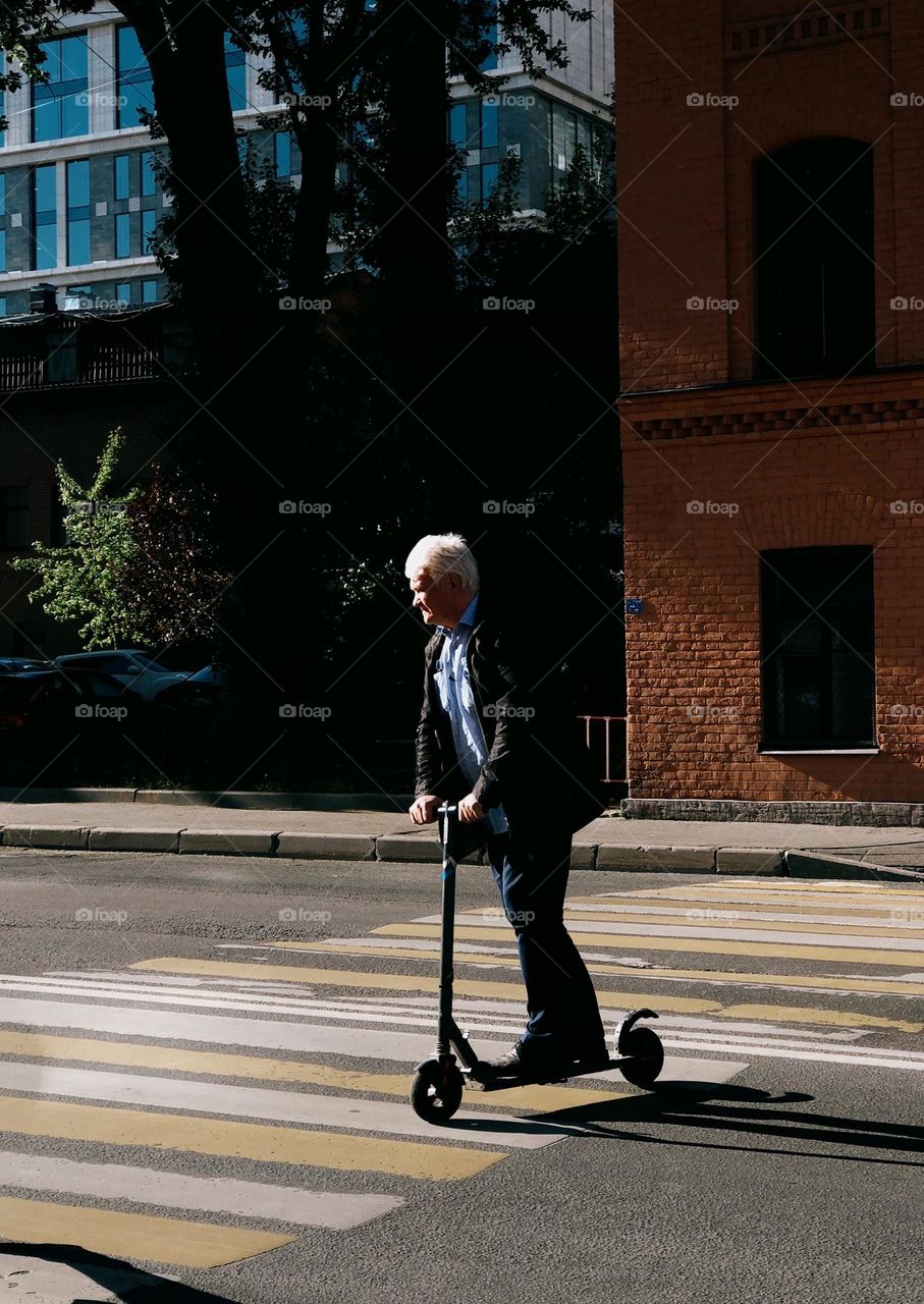 Adult man riding on the electric scooter in sunny day